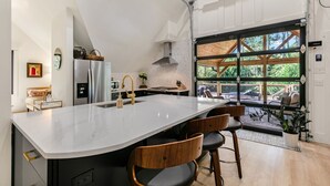 Cocina moderna con una isla grande, electrodomésticos de acero inoxidable y vistas al exterior.