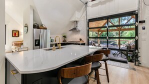 Cocina moderna con una isla grande, electrodomésticos de acero inoxidable y vistas al exterior.