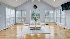 A spacious room with a high ceiling, skylights, a ceiling fan, a large window, and a flat-screen TV mounted on the wall. - 'The Mirror' - Elegant & Dog-Friendly DMV Home (Upper Marlboro)