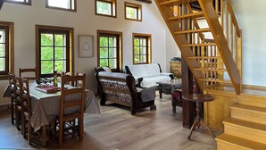 Ein Essbereich mit Holztisch und Stühlen, einer Couch und einer Treppe.