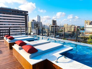 A rooftop pool area with lounge chairs and a view of the cityscape. - Flats super confortáveis no Acqua Tambaú (João Pessoa)