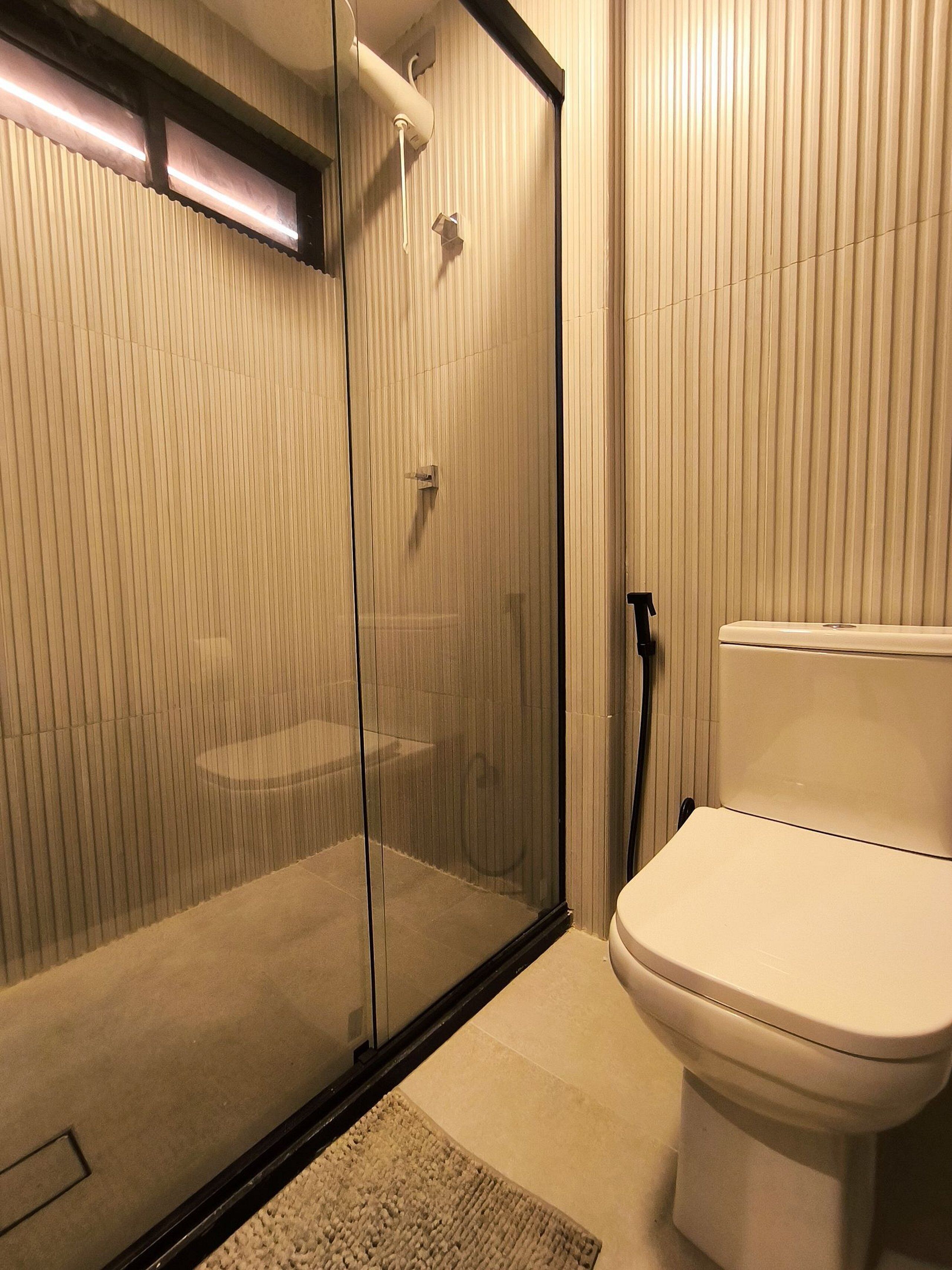 Une salle de bain moderne avec une douche à parois de verre, des toilettes et un porte-serviettes.