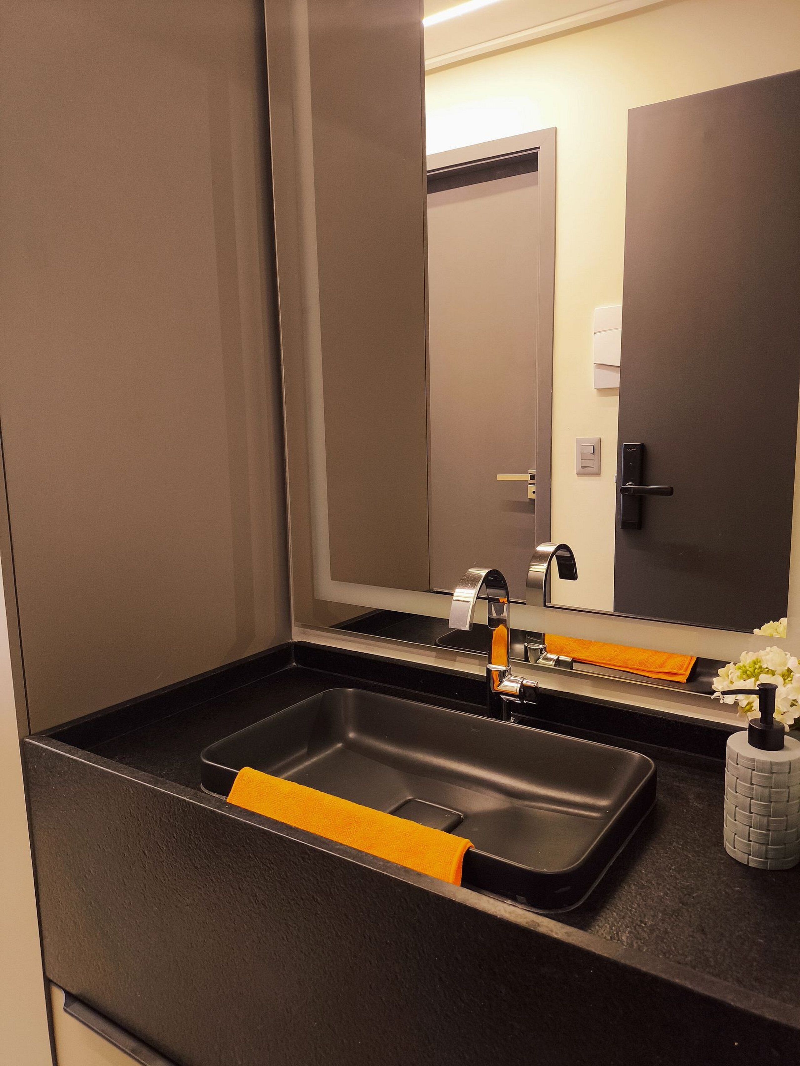 A modern bathroom with a black sink, a mirror, and a towel rack.