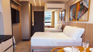 Ein Hotelzimmer mit einem Bett, einem Esstisch mit Stühlen, einem Fernseher und einem Bild an der Wand.