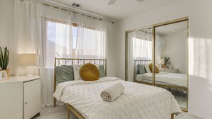 A bedroom with a bed, a bedside table, a mirror, and a window with curtains. - Golf, Fish & More! Peaceful Home in Helendale (Helendale)