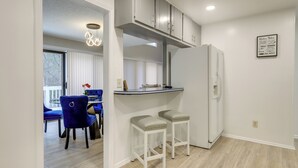 A modern kitchen with white cabinets, a built-in refrigerator, and a bar area with stools.