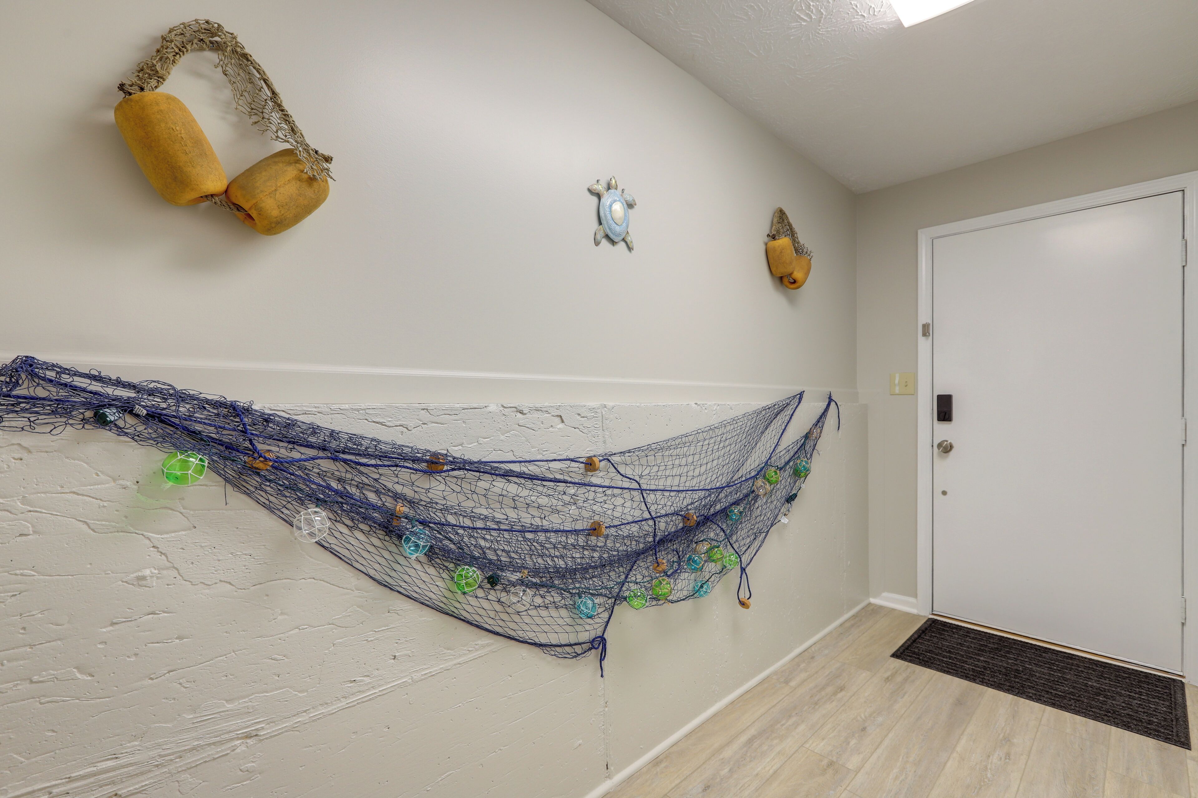 A hallway with a white door, a blue net with decorative elements, and two yellow objects on the wall.