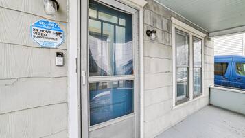Un bâtiment sur lequel est apposé un panneau indiquant une alerte de sécurité, équipé d’un système de vidéosurveillance fonctionnant 24 heures sur 24, et devant lequel est garé un fourgon bleu.