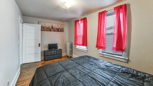 Un dormitorio con cama, cómoda, radiador y un cuadro en la pared.