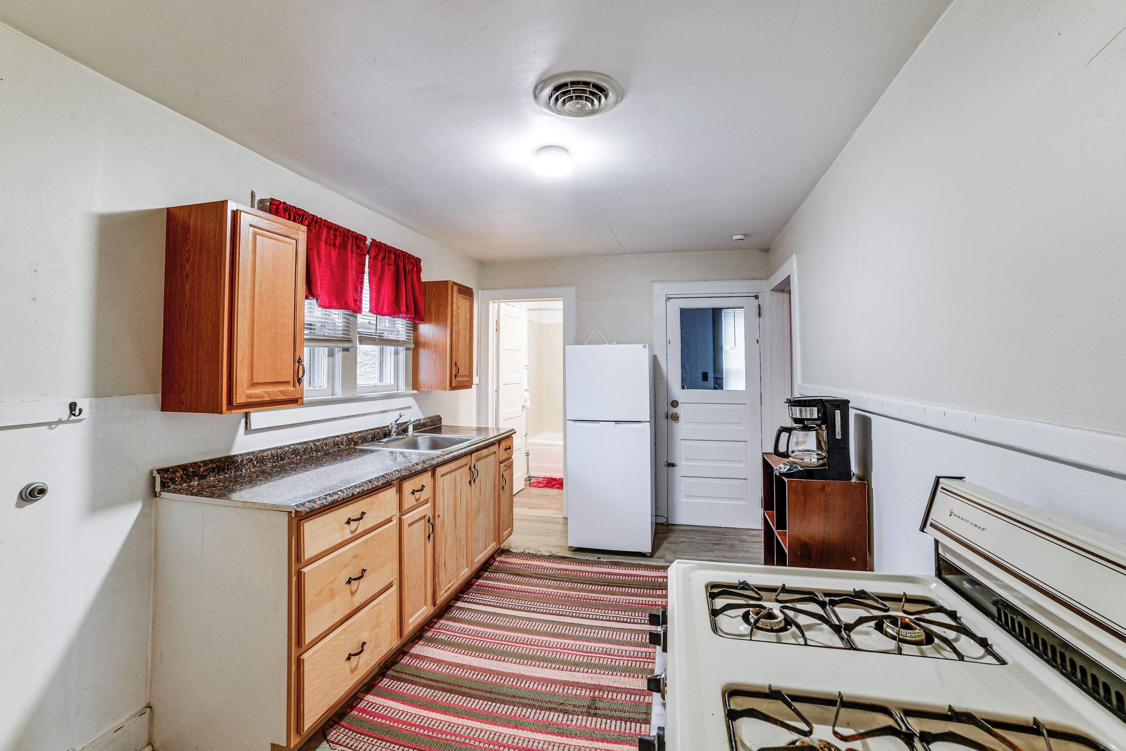 A compact kitchen with wooden cabinets, a gas stove, and a refrigerator.