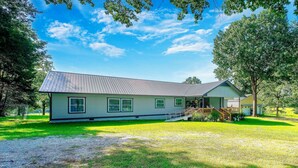 A single-story house with a sloped roof, a front porch, and a small deck. - Pool, Large Porch! Country Home Near Roaring River (Seligman)