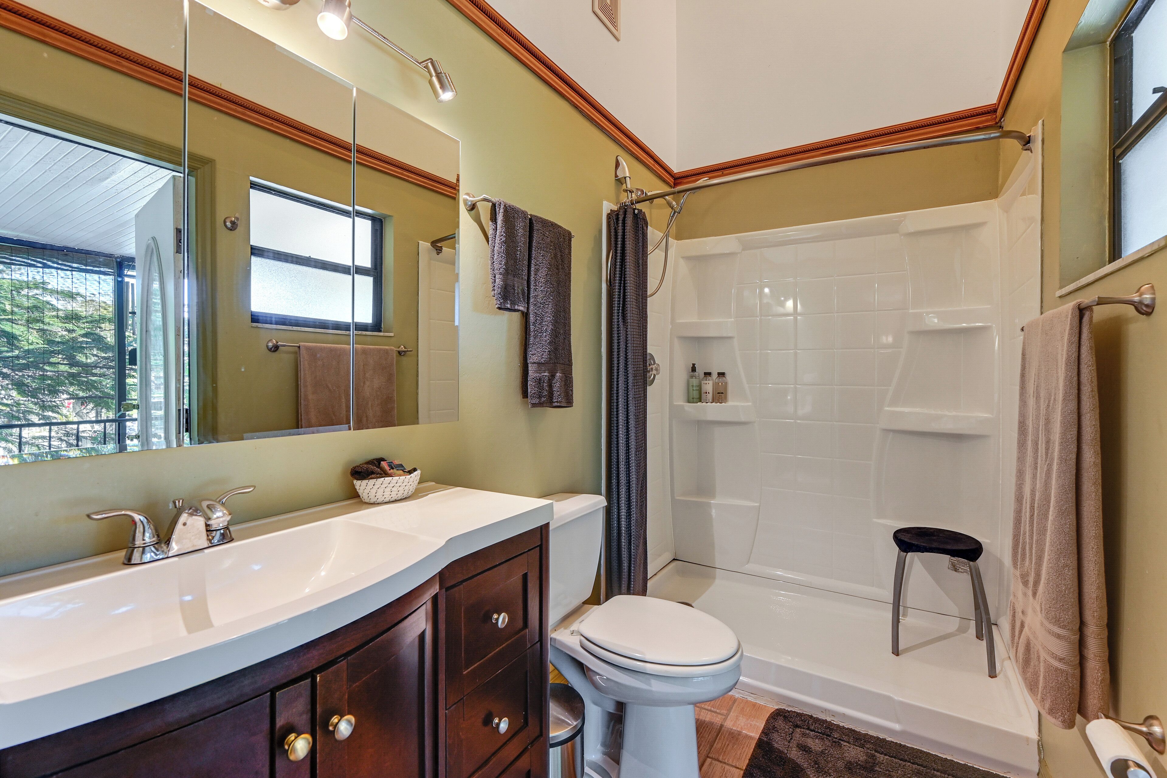 A bathroom with a large mirror, a sink, a toilet, and a shower.