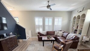 Una sala de estar con un sofá modular, una mesa de centro, un televisor y una estantería.