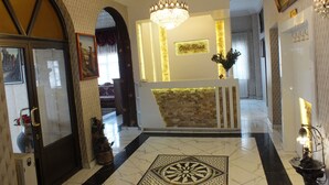 A hotel lobby with a reception desk, a chandelier, a patterned floor, and a framed picture on the wall. - OTEL NİSA (Nevşehir)