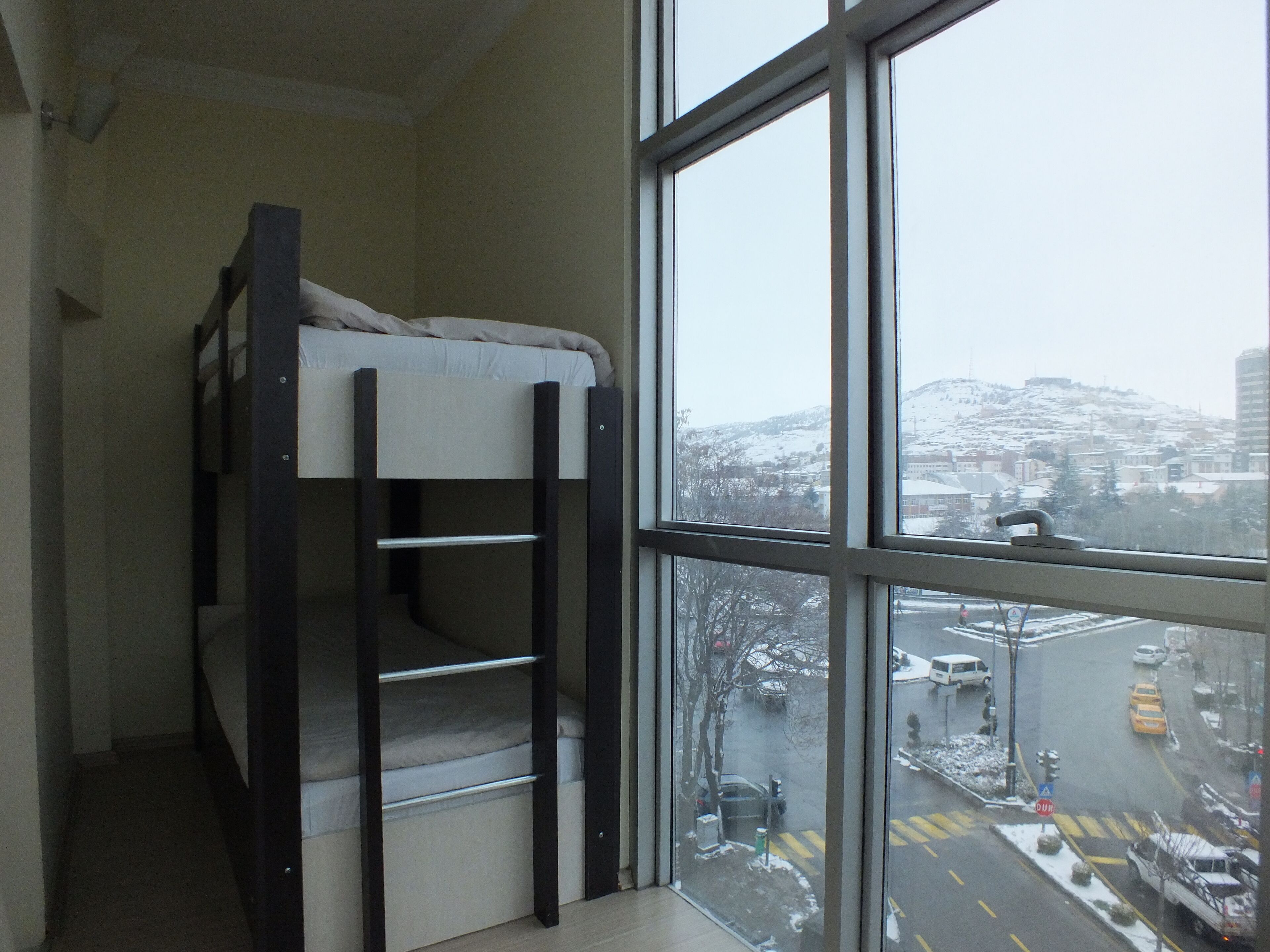 A bunk bed in a room with a large window overlooking a snowy cityscape.