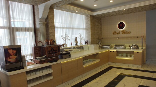A modern kitchen with a marble floor, a coffee machine, and a sign reading "Cafe Nisa". - OTEL NİSA (Nevşehir)