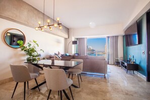 Un soggiorno moderno con zona pranzo, un'ampia finestra vista città e TV a parete.