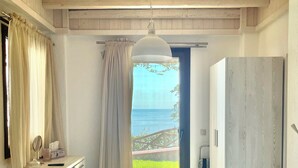 A bedroom with a bed, a desk, a wardrobe, and a view of the sea. - Koumaros Villas (Kassandra)