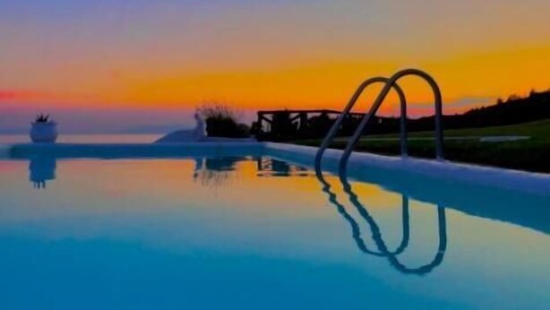 A serene pool with a clear reflection, surrounded by a calm landscape and a sunset sky. - Koumaros Villas (Kassandra)