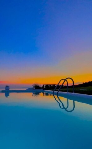 A serene pool with a clear reflection, surrounded by a calm landscape and a sunset sky. - Koumaros Villas (Kassandra)