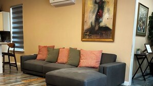 Una sala de estar con un sofá seccional, un cuadro en la pared y un piso con diseño.