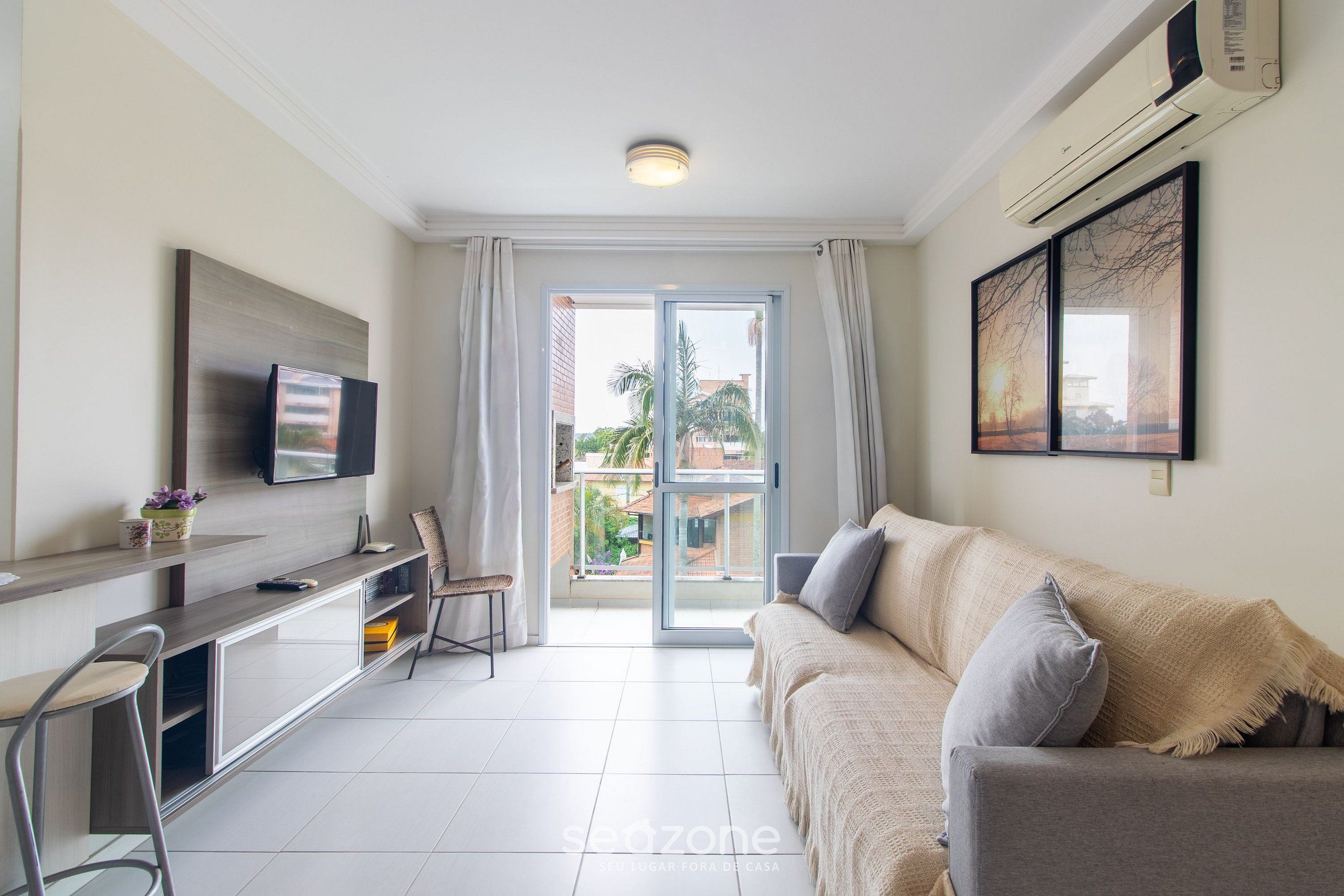 A modern living room with a sofa, TV, and a balcony with a view.