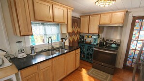 A kitchen with wooden cabinets, a black countertop, a sink, a stove, and a refrigerator.