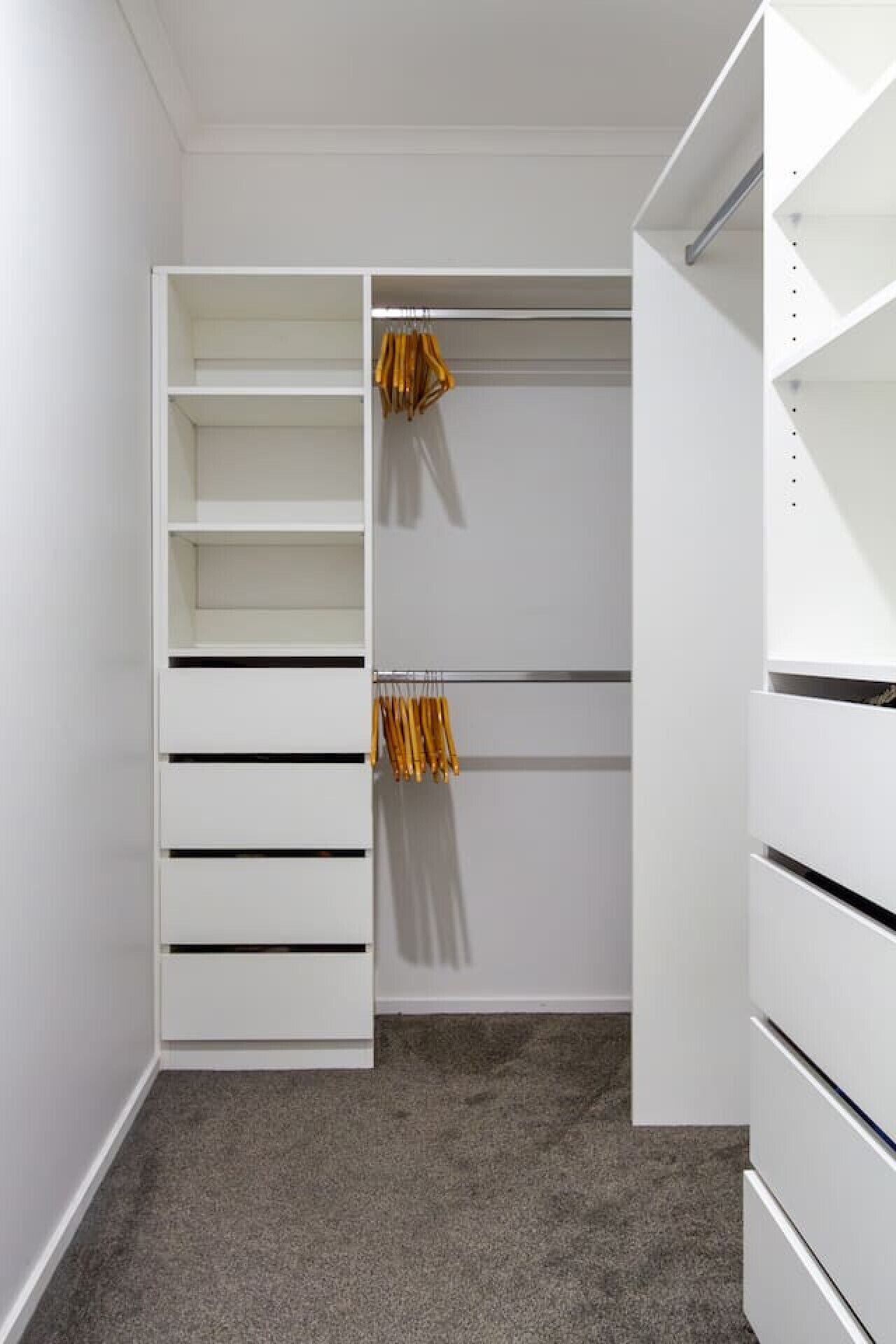 A walk-in closet with open shelves, a hanging rod, and a folded chair.
