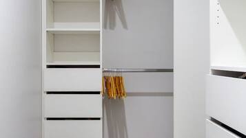 A walk-in closet with open shelves, a hanging rod, and a folded chair.