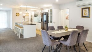 Une cuisine moderne dotée d’un îlot central, un coin repas avec une table et des chaises, et un espace de vie comprenant un canapé et un téléviseur.
