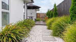 Une maison moderne dotée d’un patio, d’une clôture en bois et d’un chemin de gravier.