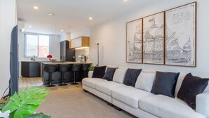 Un salon moderne comprenant un canapé, un coin cuisine et un bar pour prendre les repas.