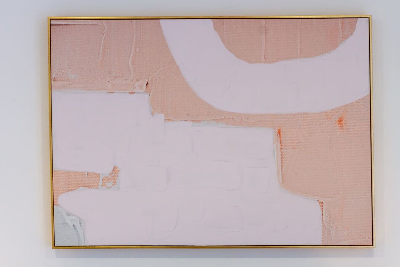 A minimalist abstract painting with a gold frame, featuring large blocks of white and peach tones.