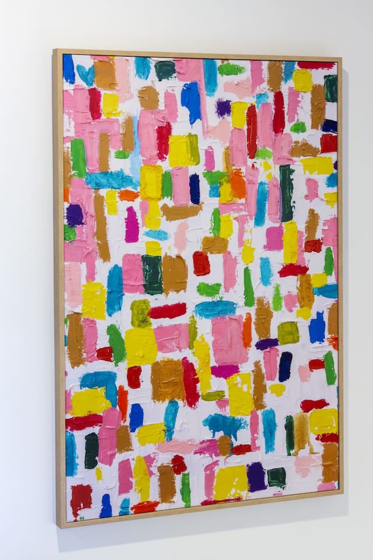A colorful abstract painting with a wooden frame on a white wall.