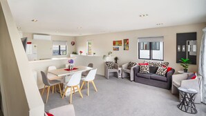 Ein modernes Wohnzimmer mit Essbereich, grauen Sofas und einem kleinen Beistelltisch.