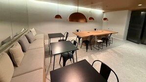 Un intérieur moderne avec une table à manger en bois, des chaises noires, un canapé beige et des luminaires suspendus.