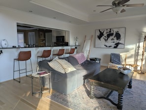 A modern living room with a grey sofa, a coffee table, and a dining area with bar stools. - The Cove At Smith Lake – Lakefront Retreat (Arley)