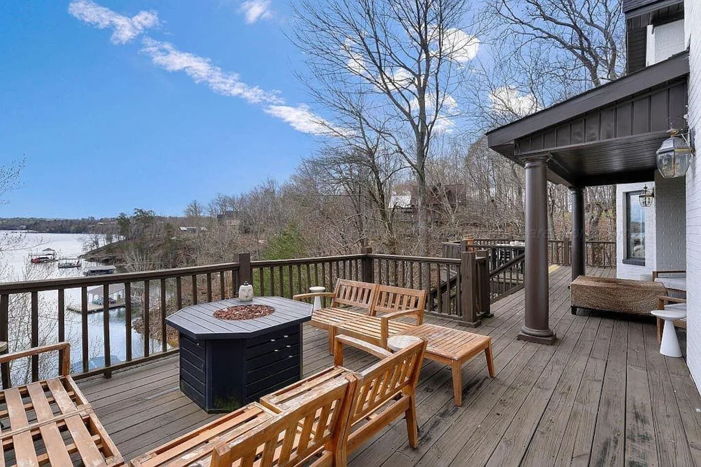 Une terrasse en bois avec des meubles d’extérieur, un barbecue et une vue sur un plan d’eau.