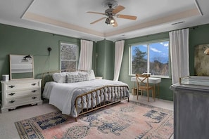 A bedroom with a bed, dresser, desk, chair, and a large window with curtains. - The Cove At Smith Lake – Lakefront Retreat (Arley)