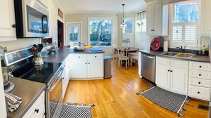Una cocina moderna con armarios blancos, una isla central, electrodomésticos de acero inoxidable y vistas al patio trasero.