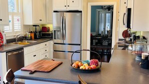 Una cocina moderna con armarios blancos, electrodomésticos de acero inoxidable y una isla central con taburetes.