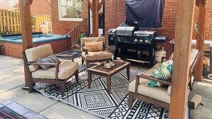 Un patio techado con una parrilla, asientos y un jacuzzi.