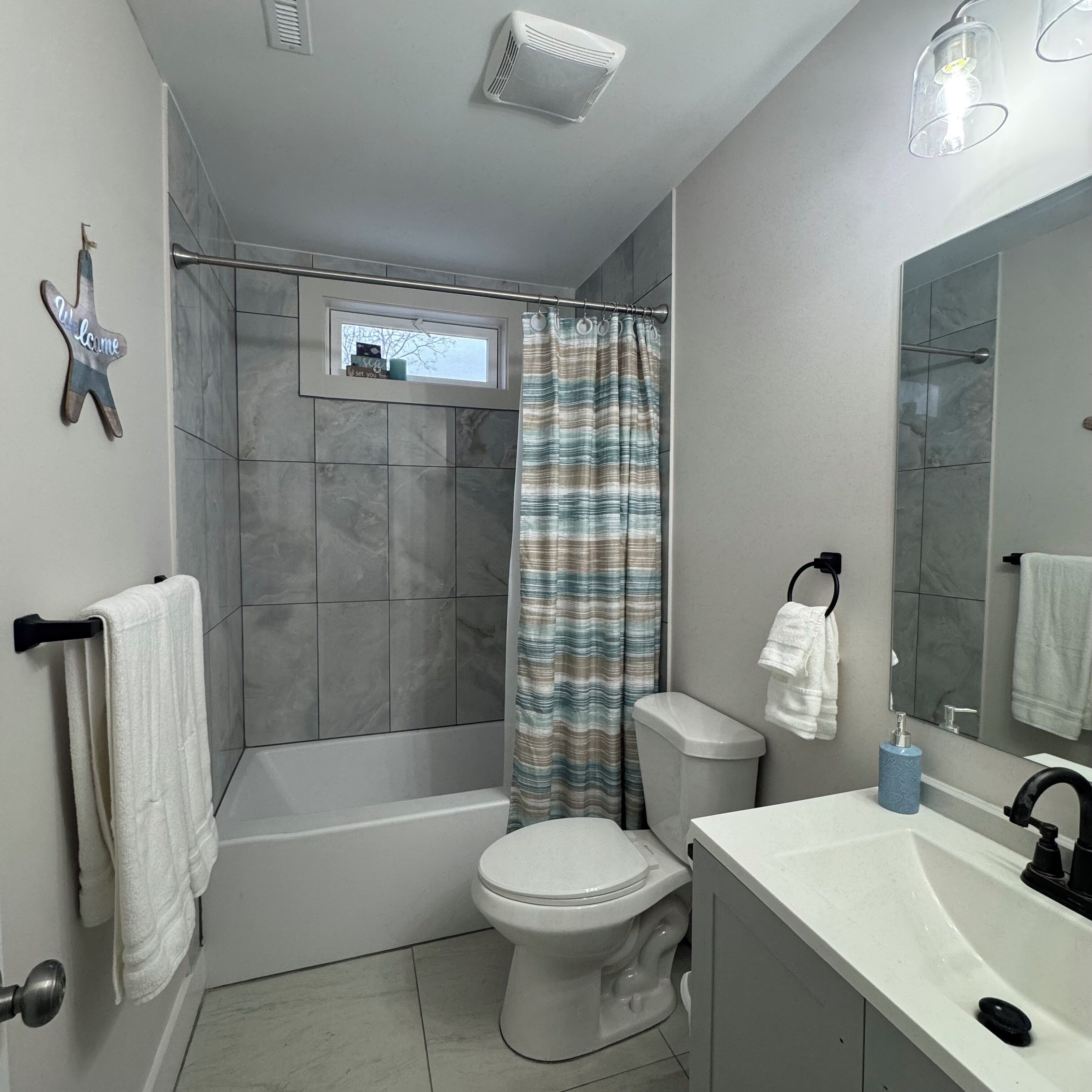 Et badeværelse med brusebad, toilet og håndvask.