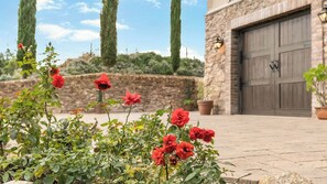 Um jardim com rosas vermelhas em frente a um edifício de pedra com porta de garagem.