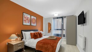 A modern bedroom with a bed, nightstand, and a mounted TV. - Cozy London Apartment With City Views (London)