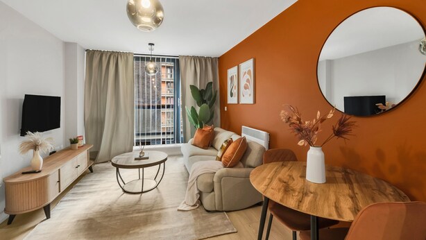 A modern living room with a sofa, a round wooden table, a TV, and a large window with curtains. - Cozy London Apartment With City Views (London)