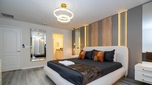 A modern bedroom with a large bed, bedside tables, a mirror, and a ceiling light fixture. - 2406 - Great Family Home Near Disney, Pool. (Kissimmee)