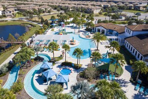Un resort con una piscina grande, palmeras y un tobogán.
