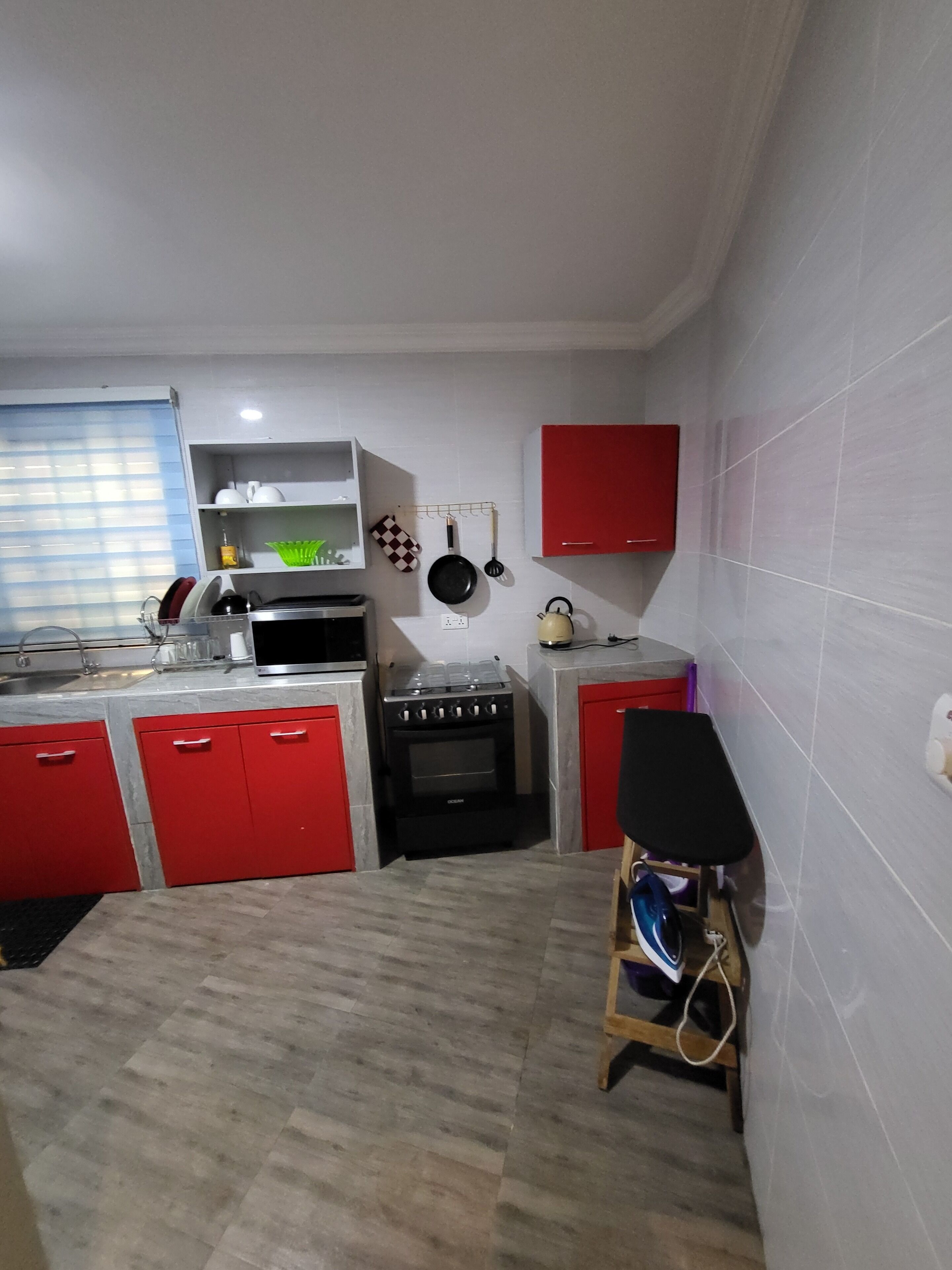 A compact kitchen with red cabinets, a gas stove, and a small oven.