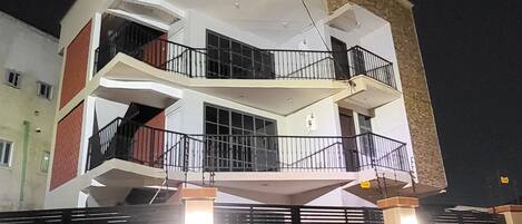 A multi-story residential building with a central courtyard, balconies, and a gated entrance.